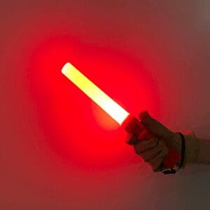 Hand holding a glowing red light stick against a dark background.
