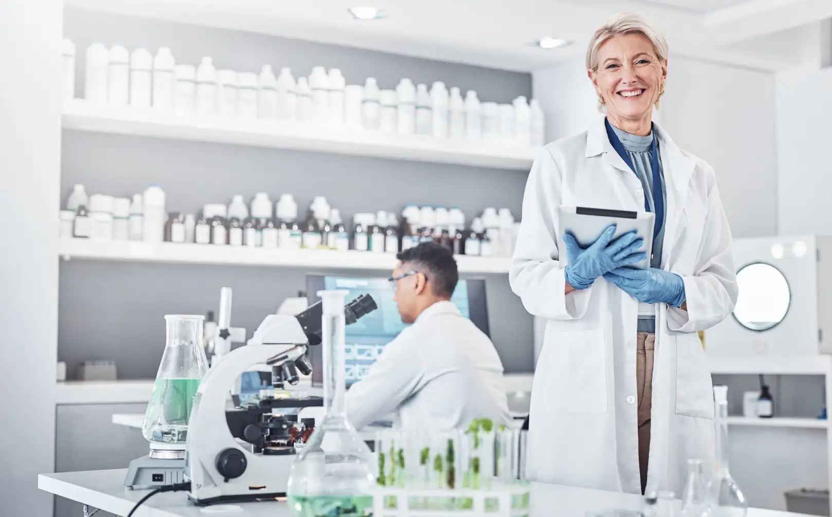 Scientist smiling in a modern laboratory setting.