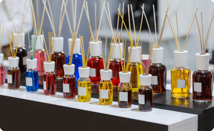 Various reed diffusers with colorful oils arranged on a table.
