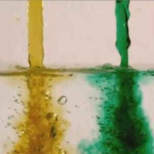 Yellow and green paint dripping down a white tiled surface.