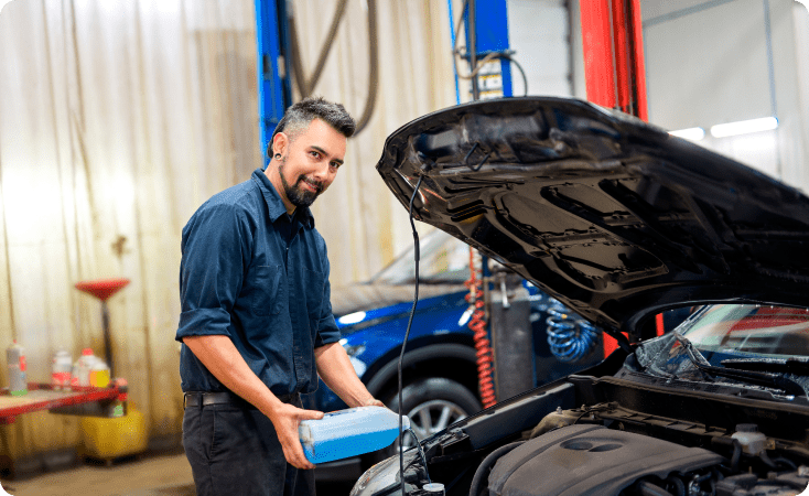 Man pouring oil into a car engine during maintenance.